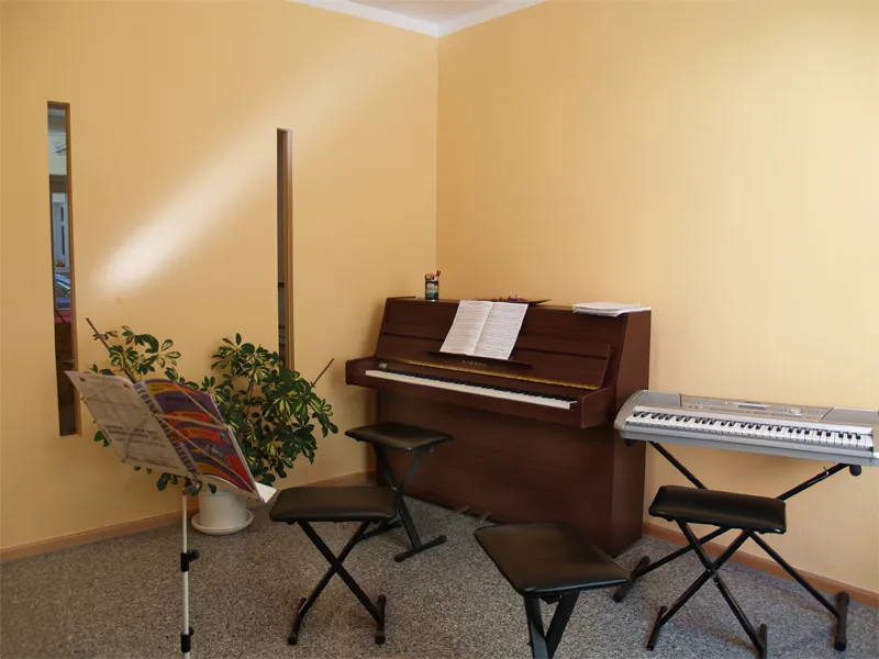 Unterrichtsraum mit Klavier, Keyboard und Notenständer